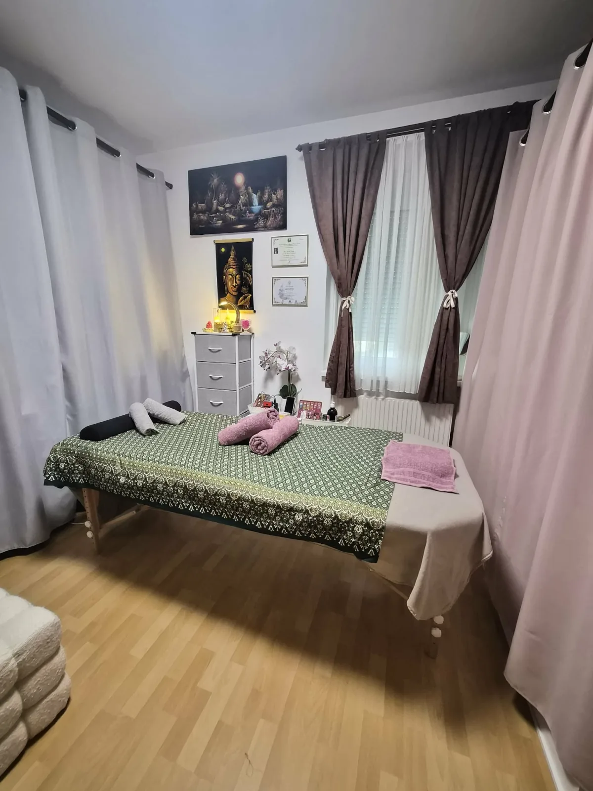 Massageliege mit grüner Thai-Decke und Handtüchern